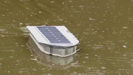 Close-up-of-a-radio-controlled-solar-boat-sailing-through-a-pond-while-it's-raining