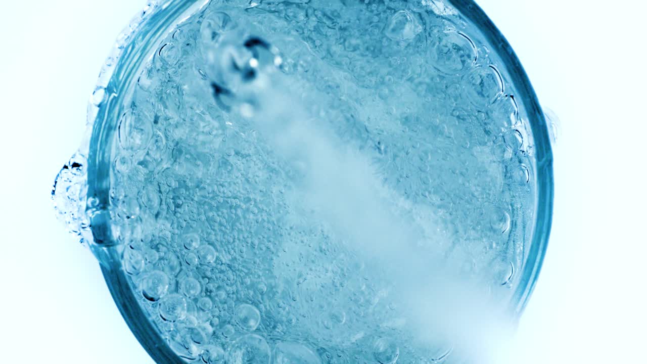 병에서 신선한 순수한 스파클링 물을 잔에 부어. 슈퍼 슬로우 모션으로 물에 거품이.