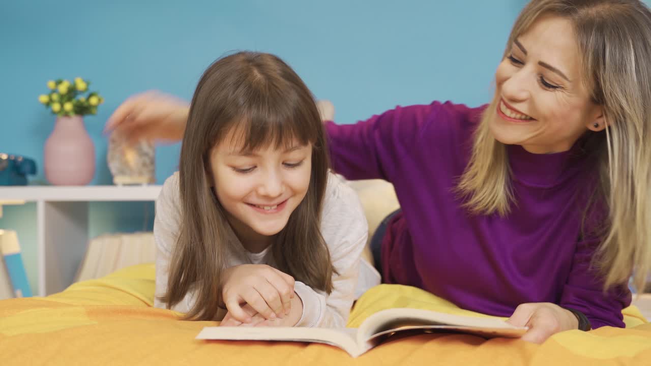 Madre e figlia felici che leggono un libro a casa.