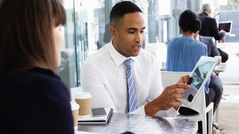 Businessman-discussing-over-digital-tablet-with-colleague-