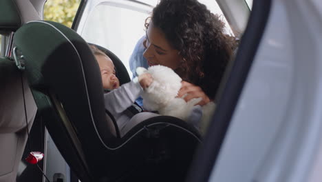 madre joven poniendo al bebé en el asiento del coche asegurando al niño para el viaje por carretera padre responsable cuidando de los niños pequeños seguridad en el vehículo