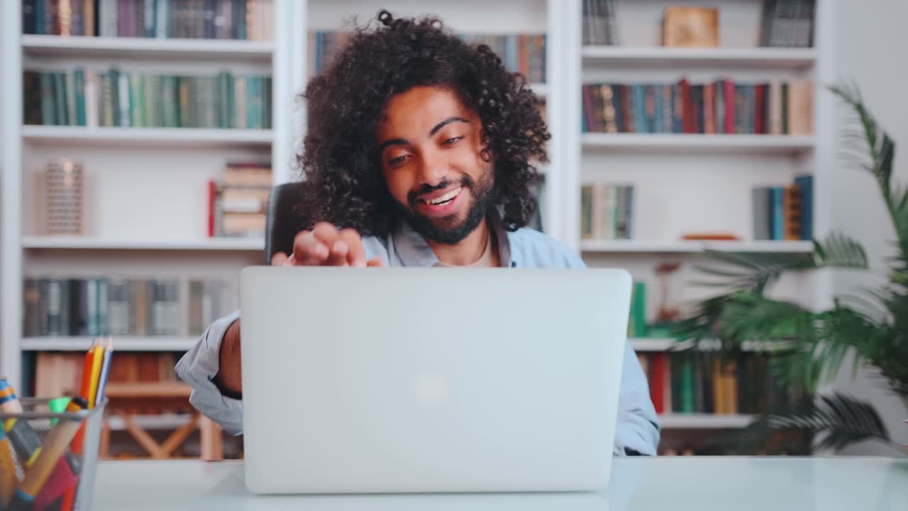 Young arabian man freelancer with smile opens laptop starts typing