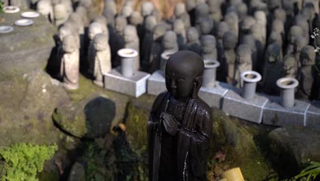 female hand pouring a buddha statue with numerous buddha figures in the background - medium shot