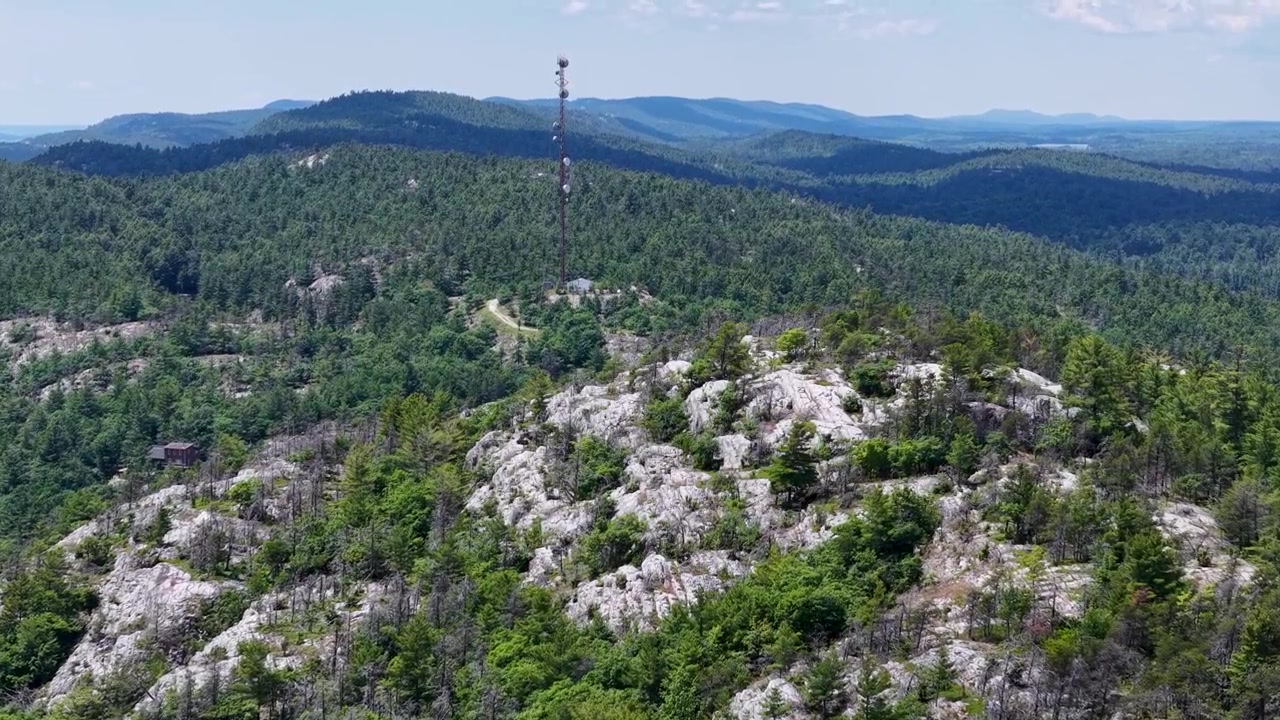 Cinematische luchtopnamen tonen bleke granietrotsen omringd door dicht groenblijvend bos in de Canadese wildernis.
