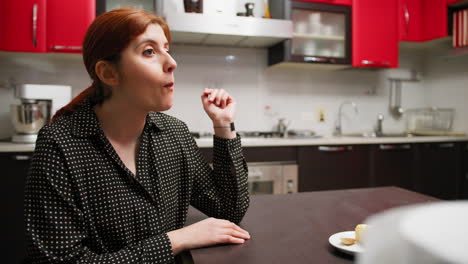 woman sings while eating cookies she made while sitting at the table