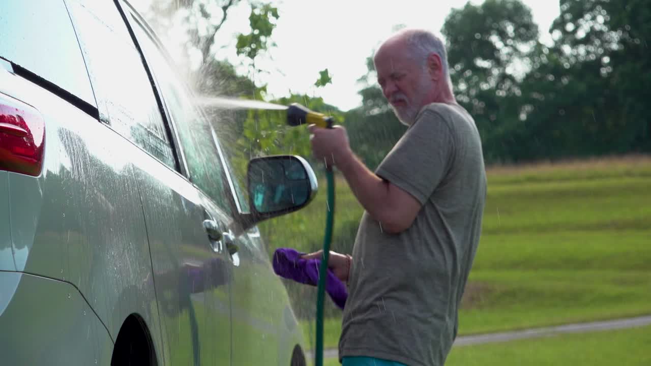 그의 차를 세차하고 호스와 비눗물 걸레로 춤추는 남자의 슬로우 모션