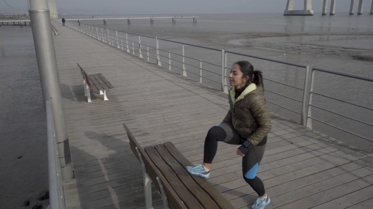 Cheerful young woman wearing sport clothing training on seaside