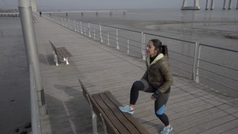 cheerful young woman wearing sport clothing training on seaside