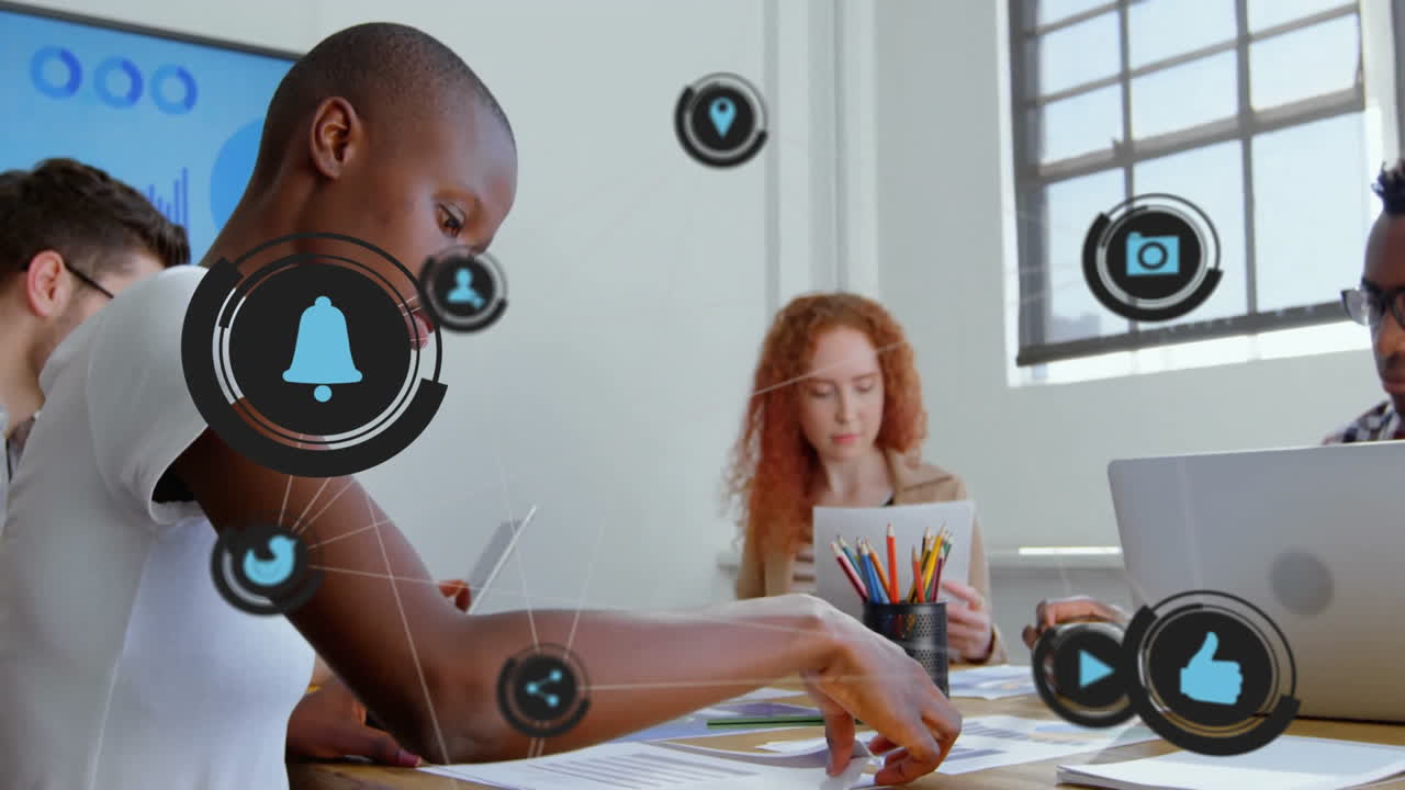 Diverse team collaborating at office with social media icons animation overlay