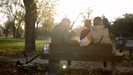 family relaxing on a bench in the park
