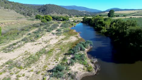 Drone aerial landscape of Murrumbidgee River creek stream inlet with riverbed water embankment and surrounding countryside mountainous bushland valley Bredbo Cooma Australia nature hiking trails trees