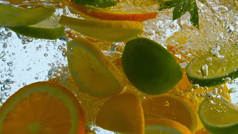 rebanadas de cítricos frescos cayendo en el agua de cerca. limón naranja en líquido.