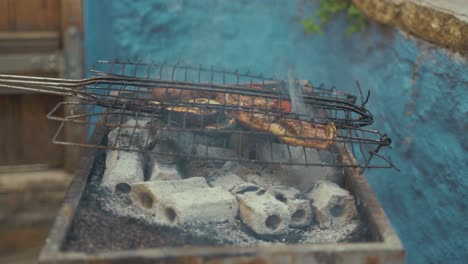 stoking charcoal on barbeque before placing steak on grill over coals