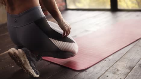 Prozess-Der-Vorbereitung-Auf-Den-Unterricht-In-Einem-Leeren-Studio-Mit-Panoramafenstern.-Junge-Frau-Rollt-Rote-Yogamatte-Im-Fitnessstudio-Auseinander