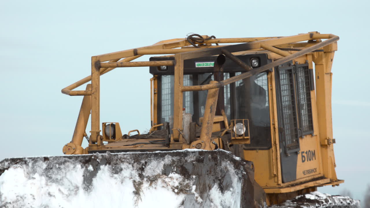 Close Up of a Yellow Bulldozer Pushing Snow and Dirt