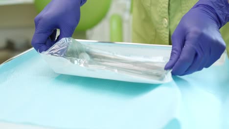 dentist hands unpacking dentistry tools. dental mirror and probe in steel plate