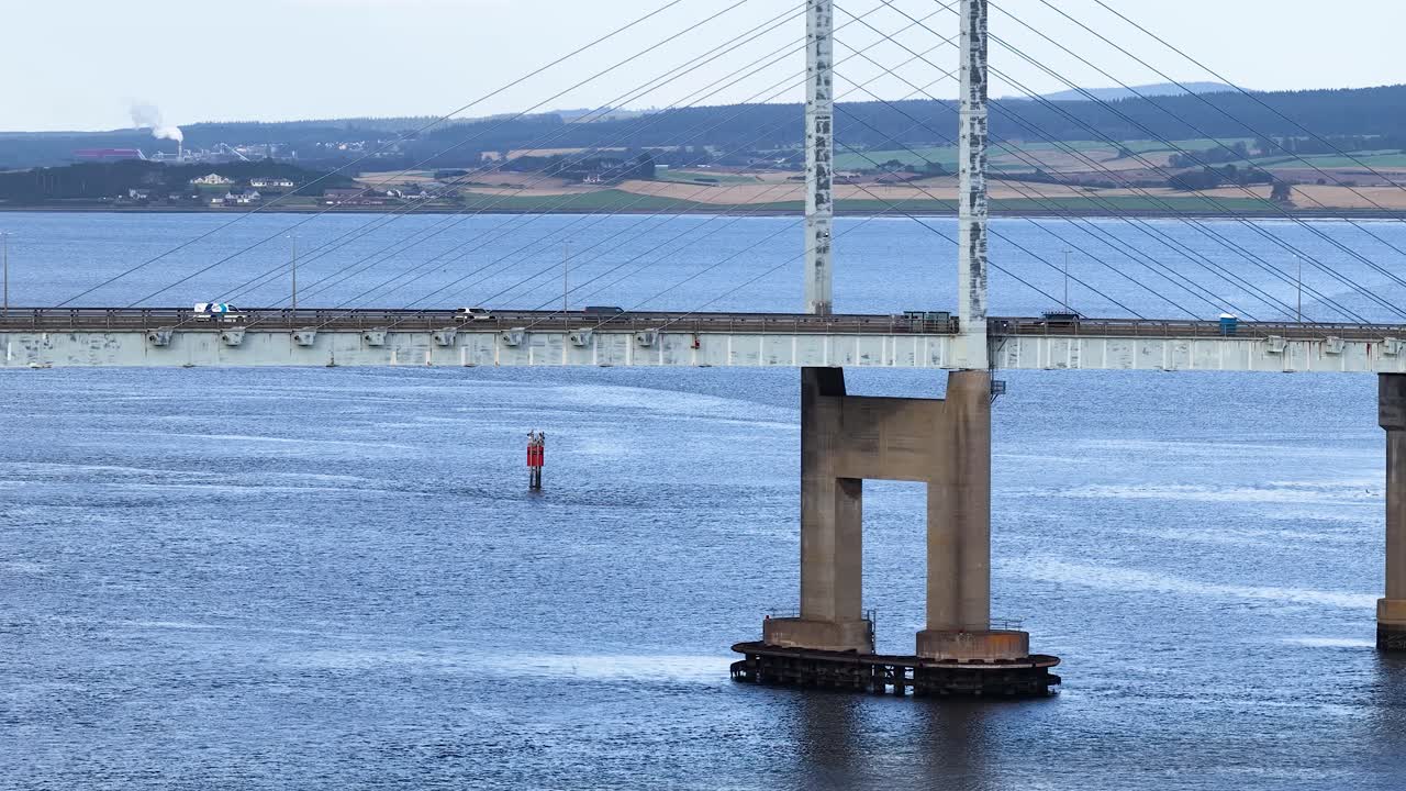 Daytime lateral pan of cable-stayed bridge, river, and countryside under soft natural lighting