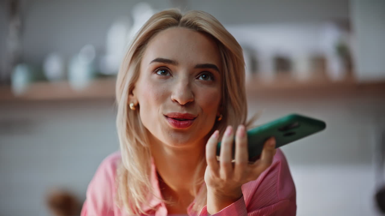 Happy woman recording voice notes at cellphone looking laptop at home portrait