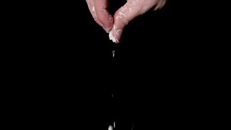 a person sprinkling the flour powder over something, isolated on black background