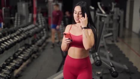 Schönes-Sportmädchen-Mit-Einem-Telefon-Im-Fitnessstudio