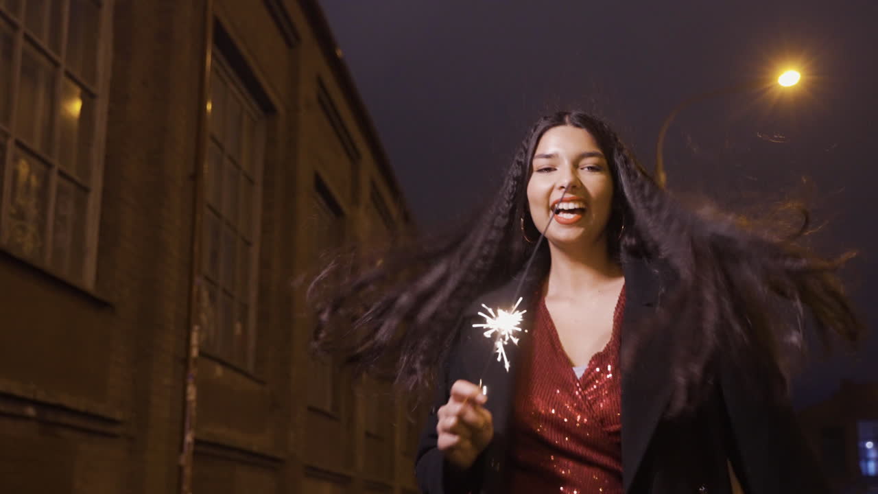 Camera Focuses On A Young Girl In Elegant Clothes Holding A Sparkler And Celebrating New Year's Eve