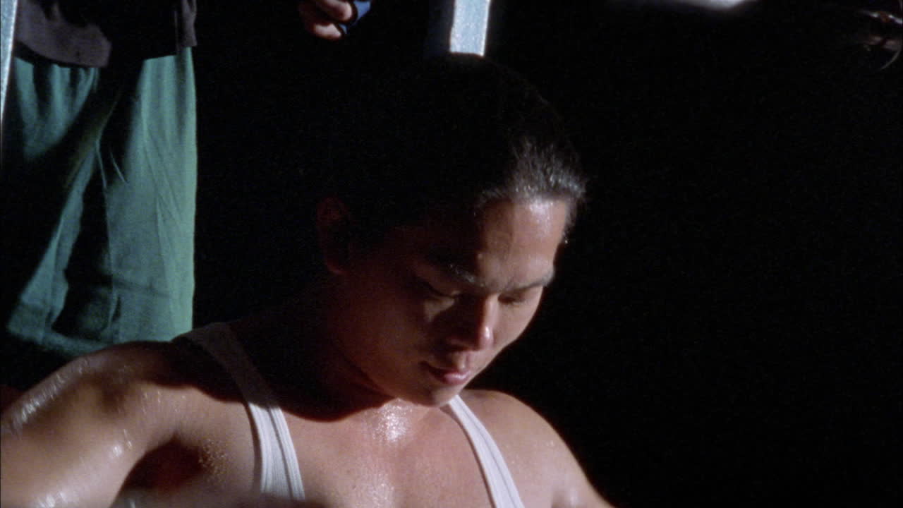 운동 기계에서 일하는 남자가 멈추고 얼굴을 닦고 다른 남자가 뒤에 서 있습니다.