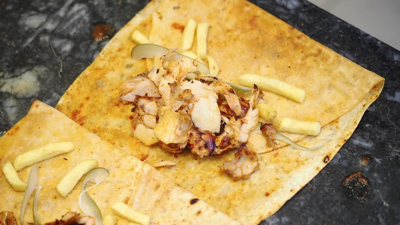 Primo piano di uno chef che prepara una piadina di shawarma di pollo