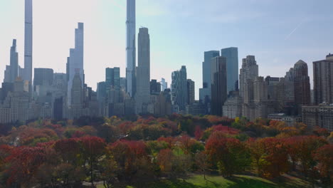 Lawn-and-autumn-colourful-trees-in-Central-park.-Historic-high-rise-buildings-and-glossy-futuristic-skyscrapers-in-city-around.-Manhattan,-New-York-City,-USA