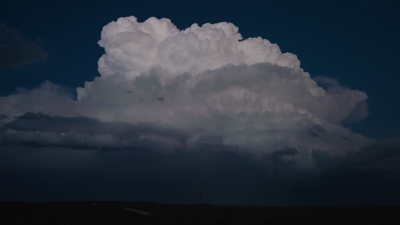 Ominous storm cloud lit by distant lightning showing power in nature at night
