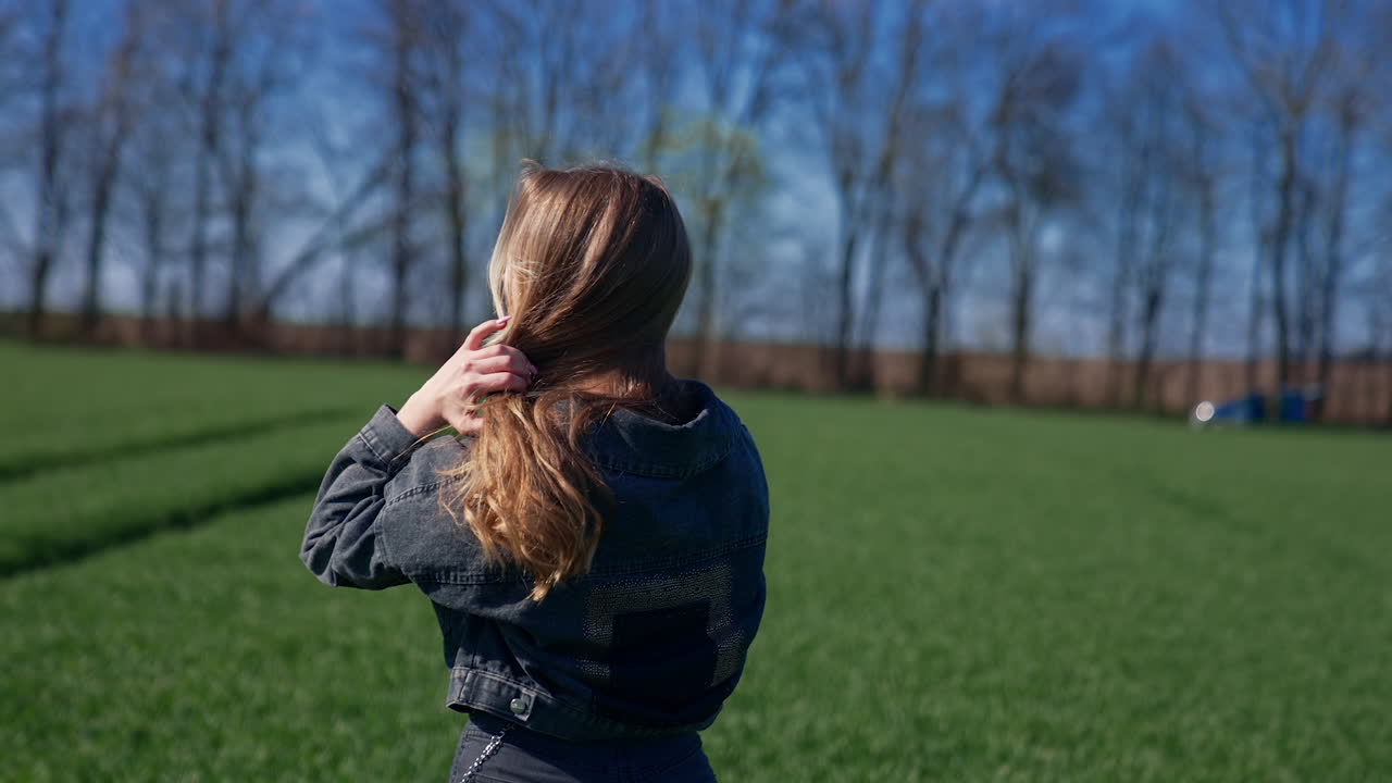 Beautiful girl in the countryside. Attractive young model with long blond hair posing on camera on the field. Orbital view.
