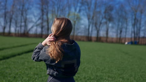 beautiful girl in the countryside. attractive young model with long blond hair posing on camera on the field. orbital view.