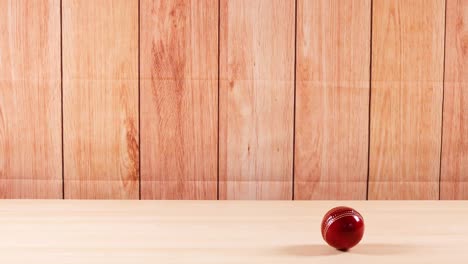 a cricket ball rolls across a wooden surface