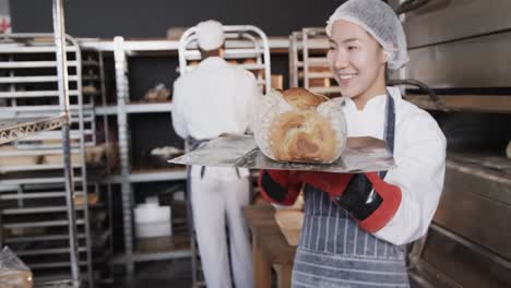 happy diverse bakers working in bakery kitchen, putting fresh bread out in slow motion