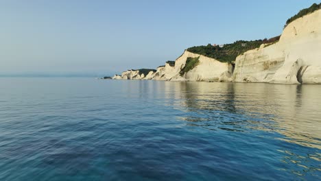 Acantilados-Iluminados-Por-El-Sol-De-La-Isla-De-Corfú-Contra-El-Sereno-Mar-Jónico-En-La-Hora-Dorada,-Plano-Amplio