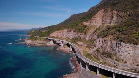 aerial view of sea cliff bridge, sunny day, grand pacific drive, australia - orbit drone shot