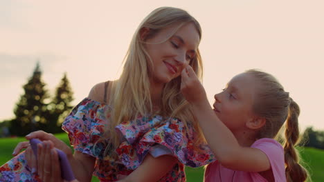 Family-speaking-in-city-park.-Mother-and-daughter-watching-film-at-meadow.