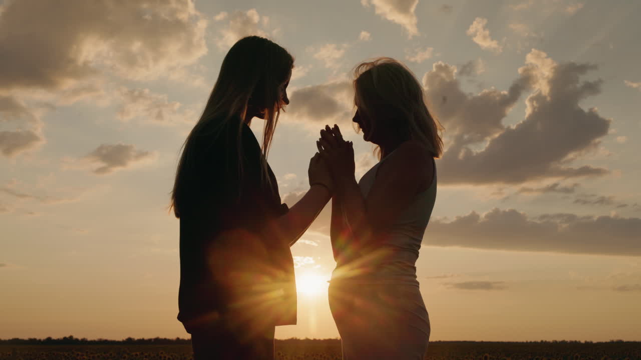 Silhouette of two women holding hands at sunset
