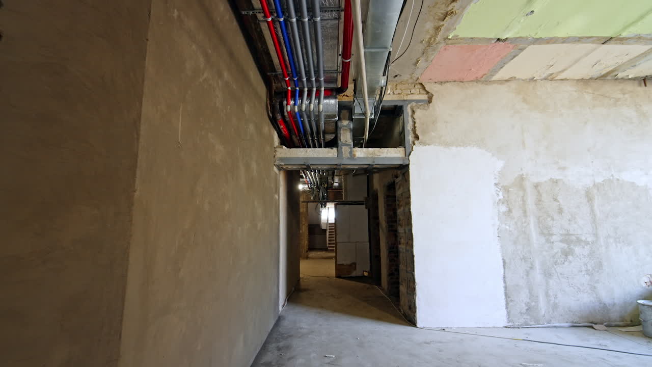 Walking by the long corridor of the renovated building. A set of wires and pipes on the ceiling. Reconstruction concept.