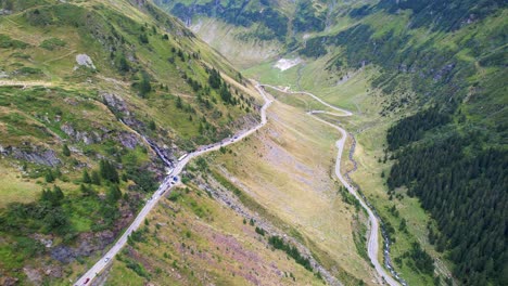 slow push in aerial dolly of transfagarasan serpentine road waterfall and valley hairpin turn