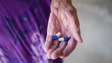 una mujer que envejece tomando sus pastillas de medicamentos de una botella de farmacia en su mano