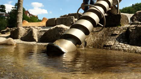 a man turns the water spiral in a children's playground on a sunny spring day