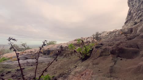 Walking-backward-on-the-rugged-and-stony-ground,-unveiling-the-distant-hills,-depicting-a-concept-of-raw-and-untamed-natural-surroundings