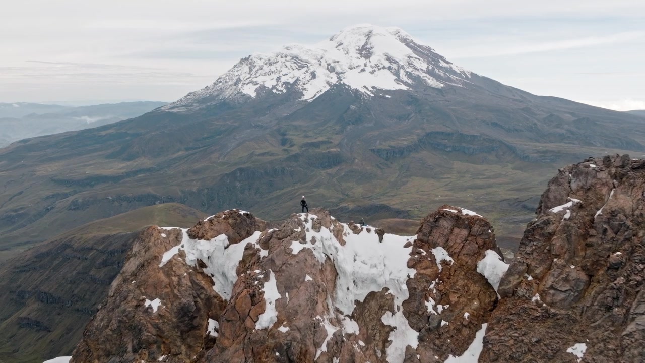 Alpinisti sulla cima del Vulcano Carihuairazo con il Vulcano Chimborazo sullo sfondo