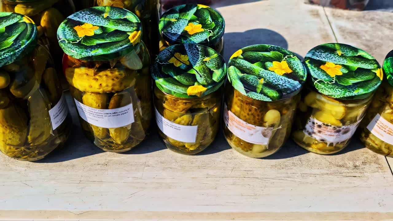 Closeup view of fresh pickles in jars arranged neatly on market counter display