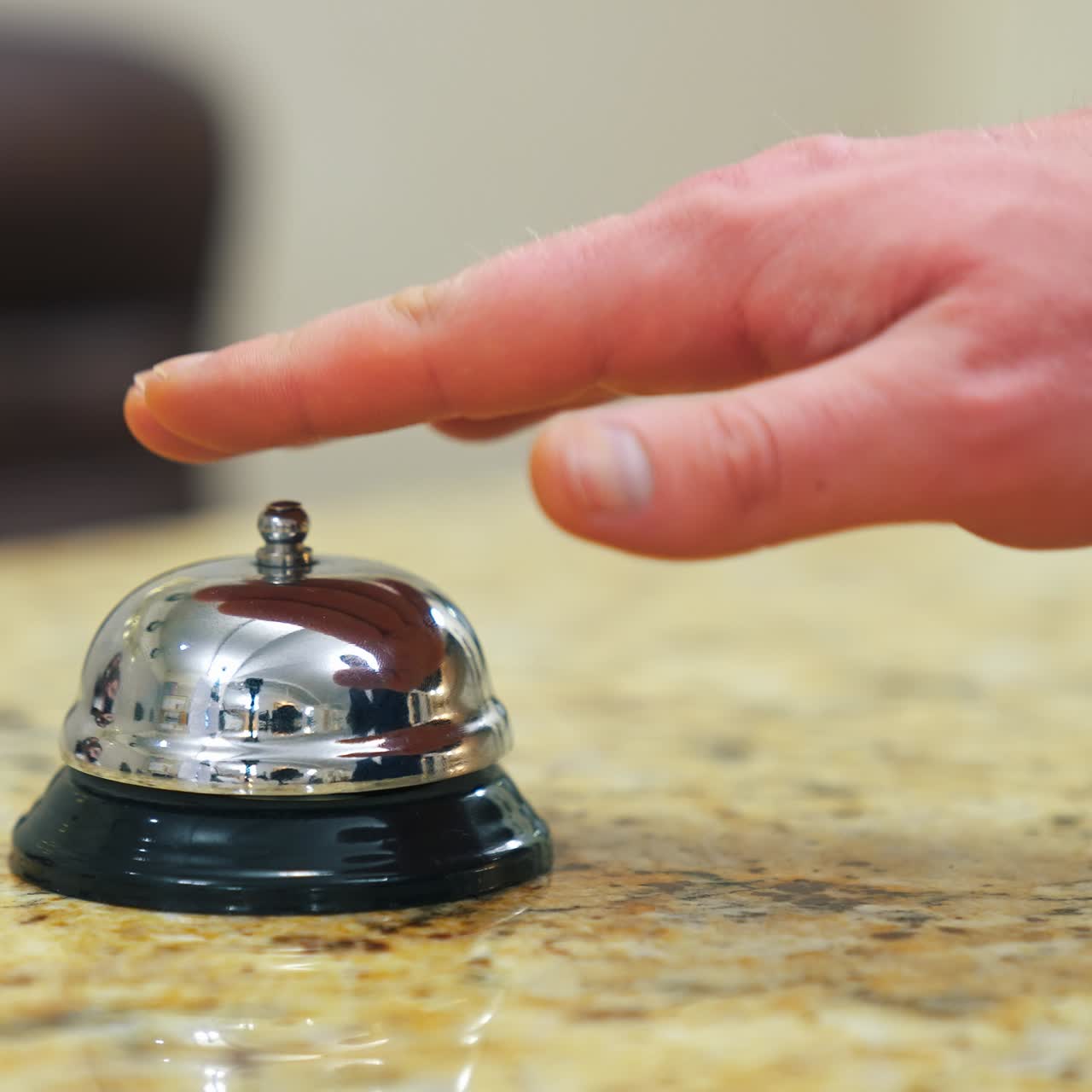 Hotel bell button on customer reception counter. The hand of the man presses the call. Bell on reception at the hotel to call the administrator. Close-up