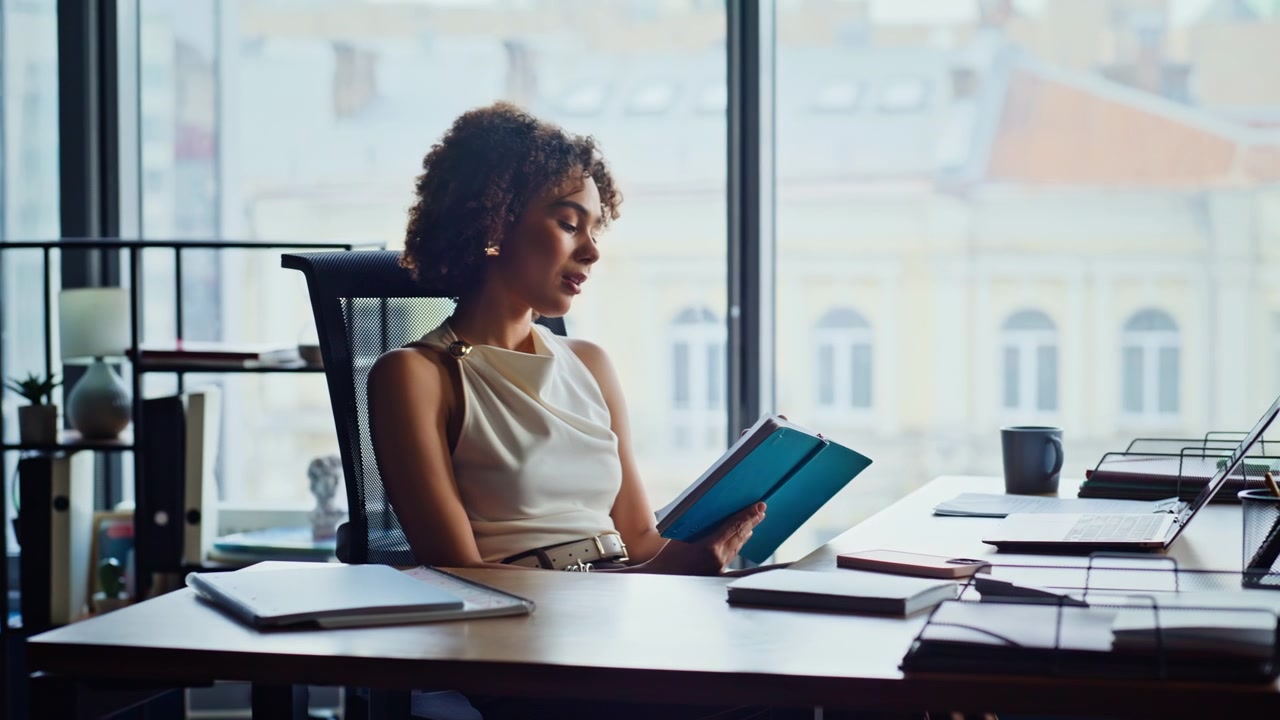 Pensive businesswoman reading notes at office window. Thoughtful woman planning