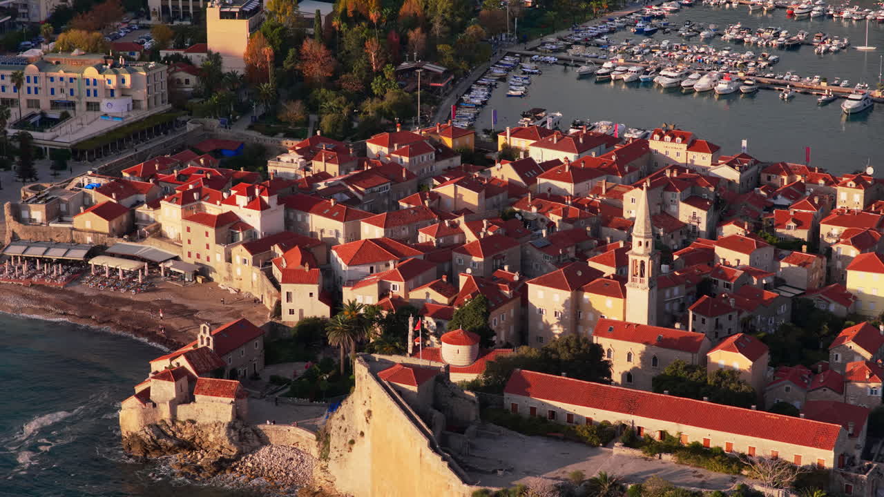 Vista aerea con drone della città vecchia di Budva, con particolare attenzione al porticciolo, al campanile e alle case compatte in pietra. Montenegro