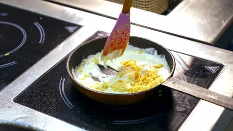 cooking food in a frying pan. chef is frying tasty dish in white sauce and mixing it with a scapula. cooking delicious meal in a restaurant.