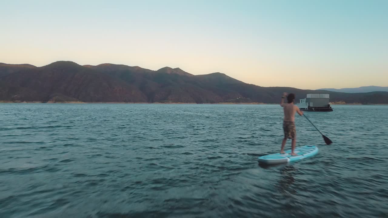 Un homme faisant du paddleboard sur un lac paisible avec des montagnes