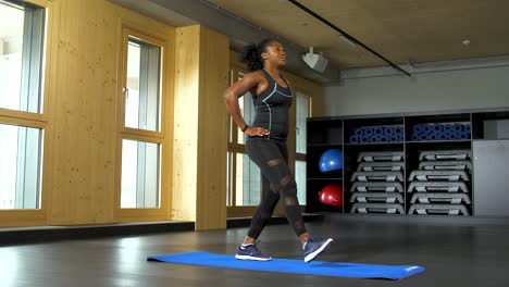 standing in a split stance, one leg in front, and slowly moving forward in one bended knee on each side as the woman dips in lunges for her exercise